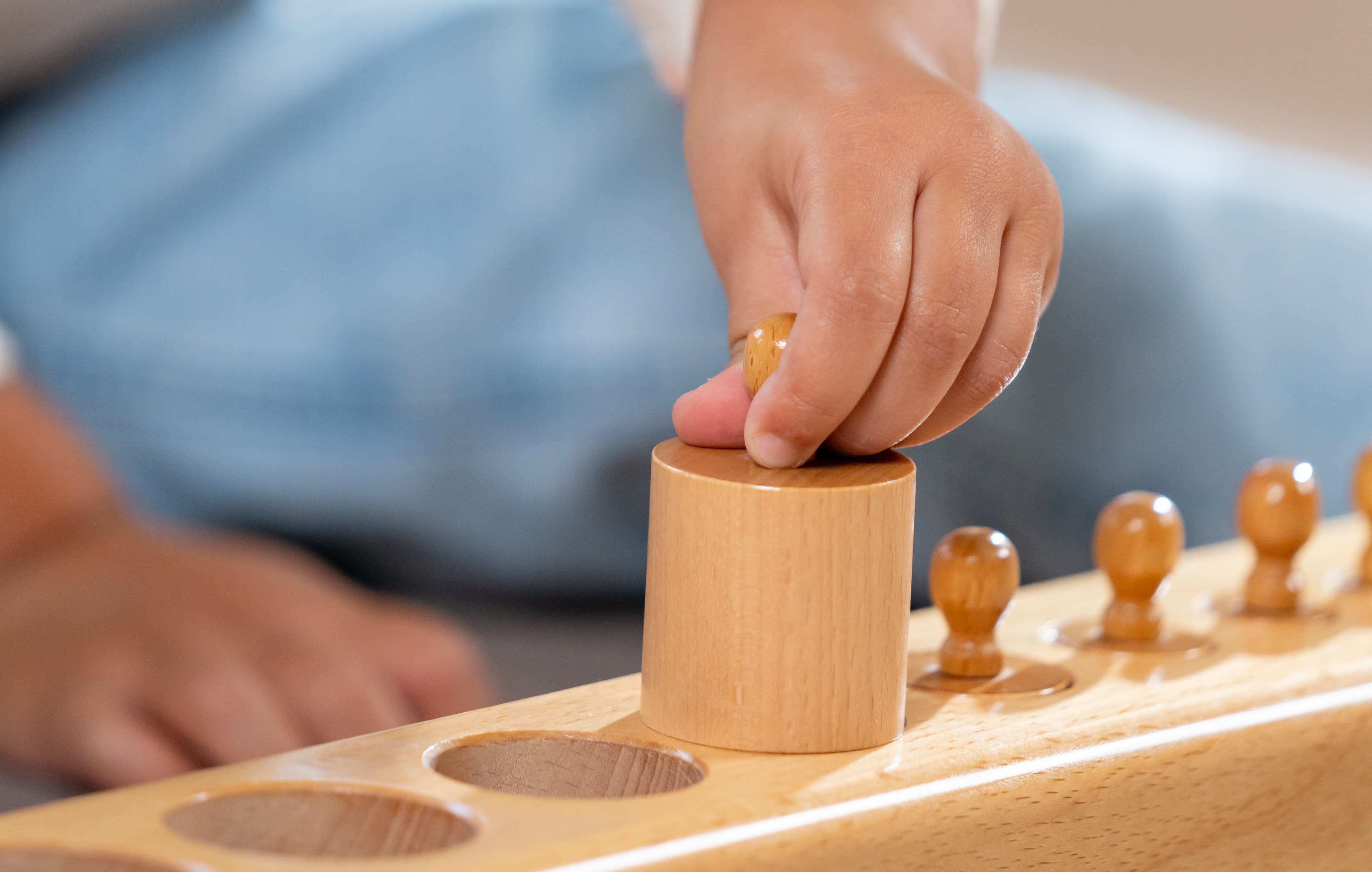 Eine Nahaufnahme von einer Kinderhand mit einem Zylinder aus dem Zylinderblock in ihren Händen.