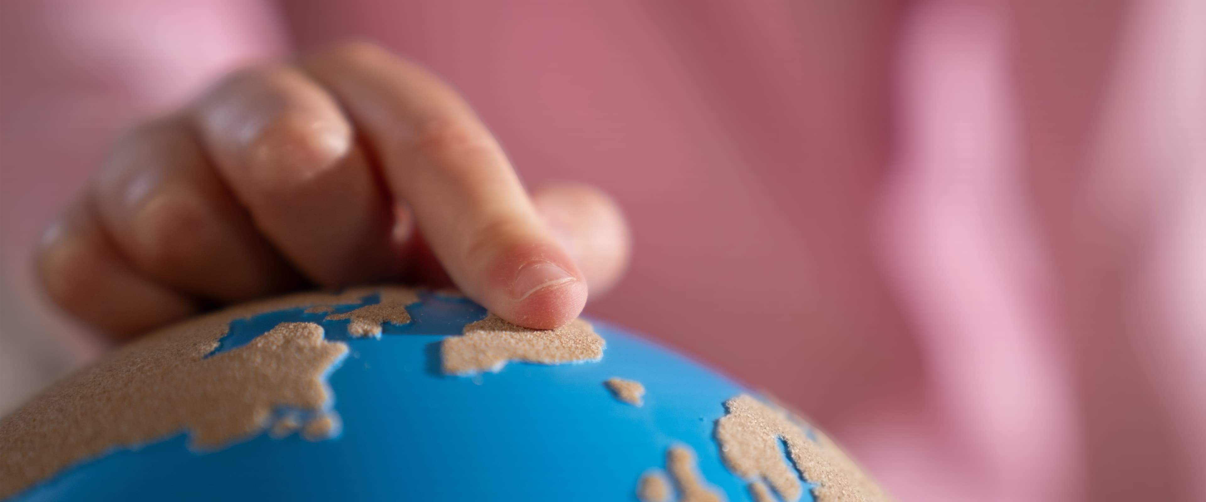 Eine Nahaufnahme von einem Kinderfinger, der einen rauen-glatten Globus von Nienhuis berührt.