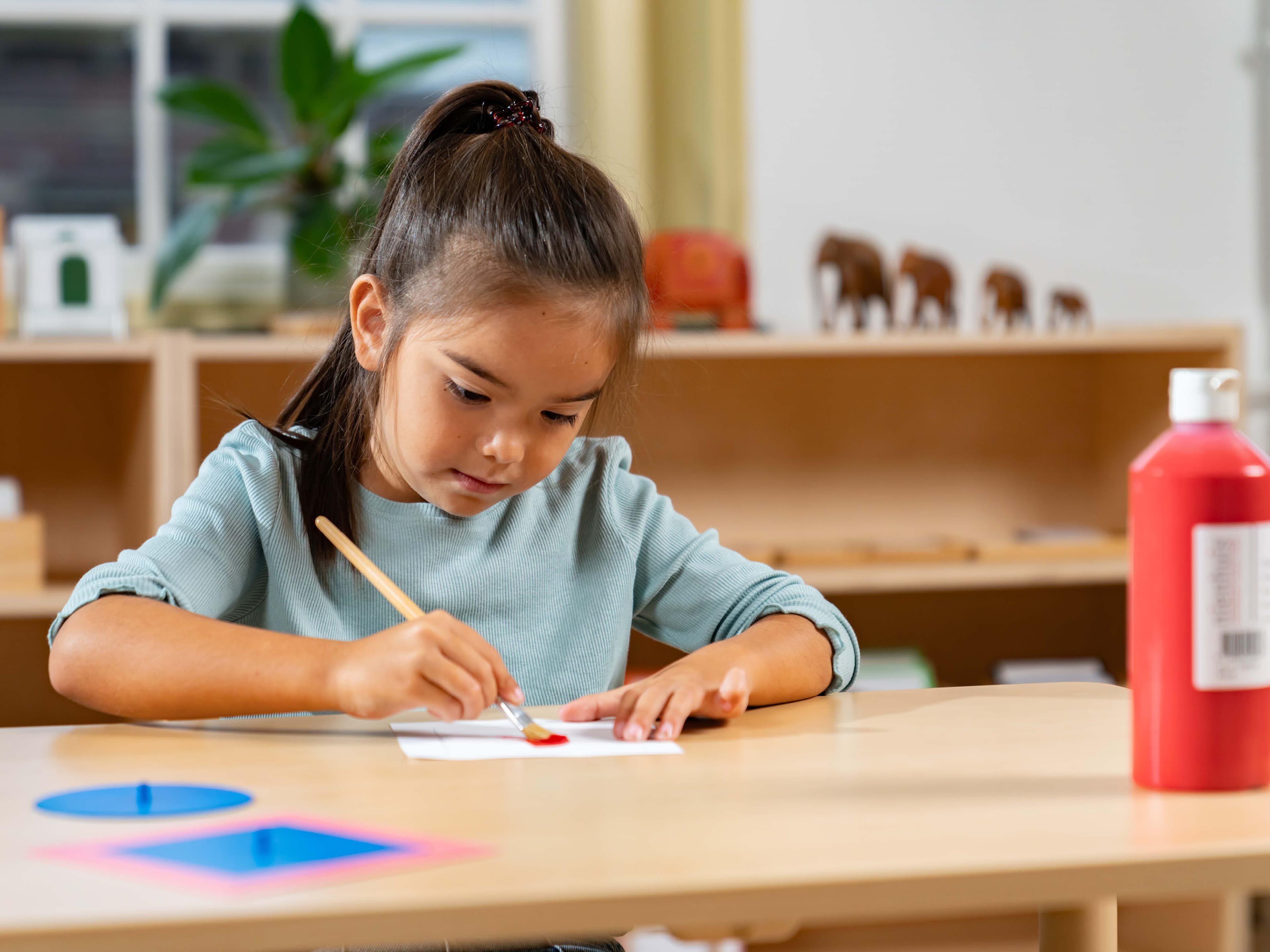 Girl painting on a table with red paint