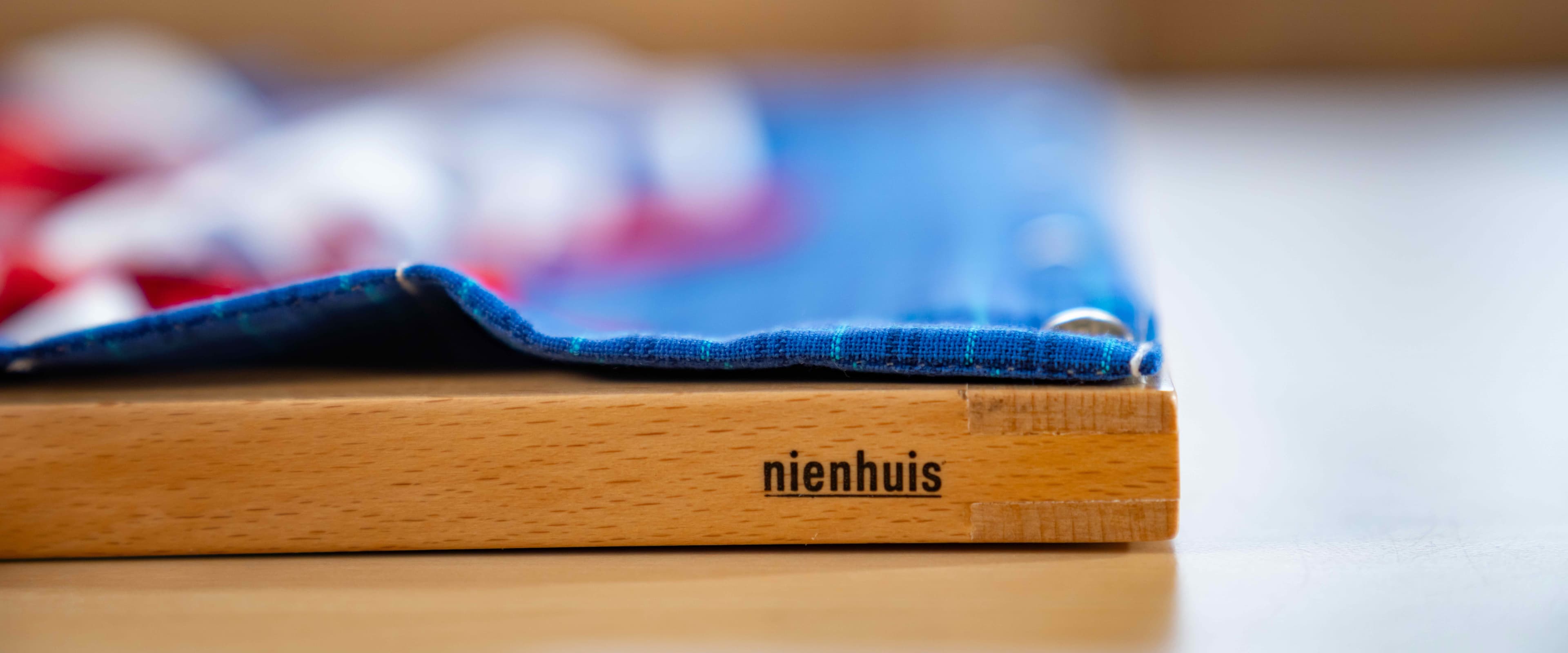 Nahaufnahme eines Nienhuis Kleinkind-Anziehrahmen, mit Betonung auf das Nienhuis-Logo.