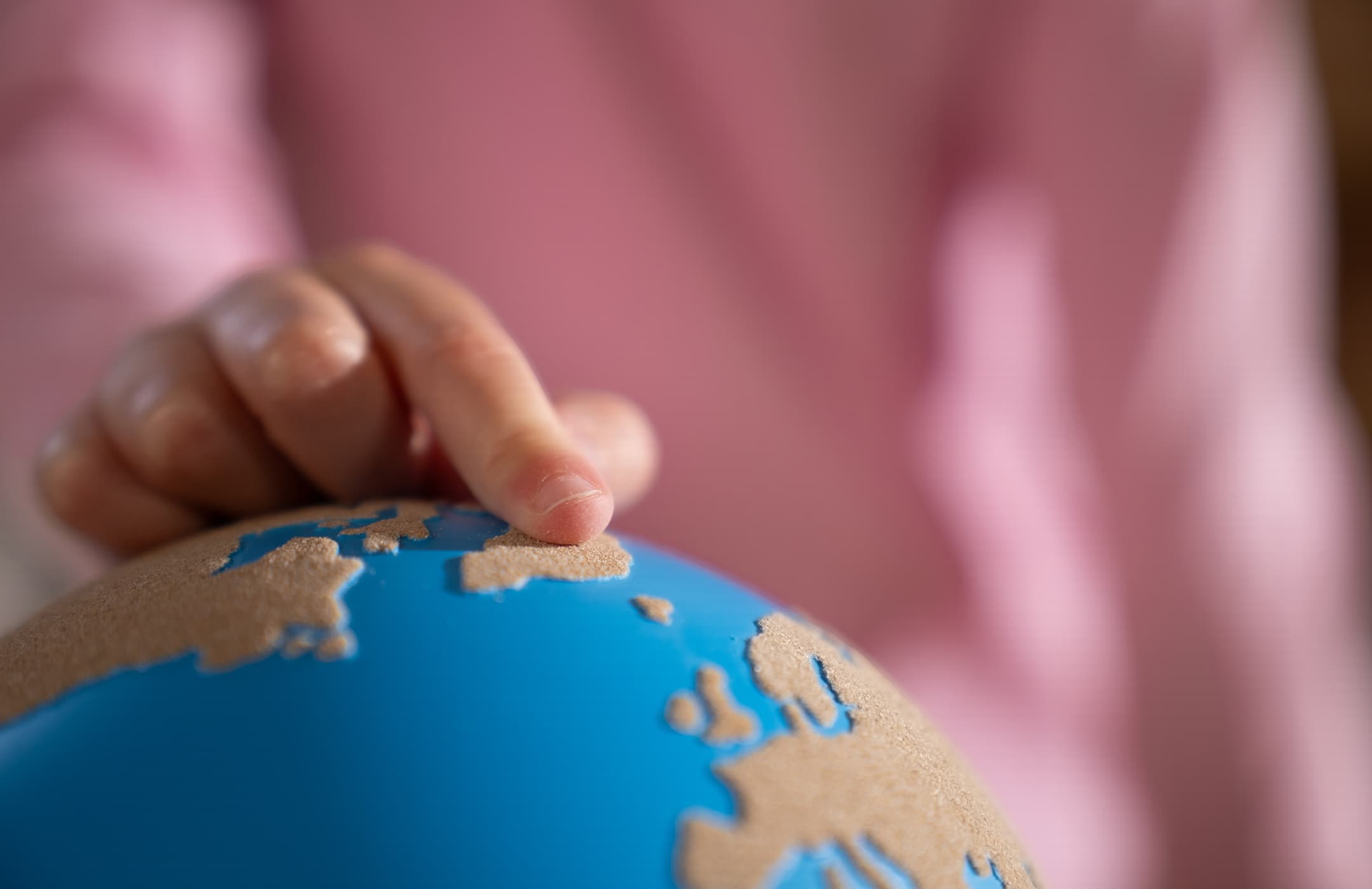 Eine Nahaufnahme von einem Kinderfinger, der einen rauen-glatten Globus von Nienhuis berührt.