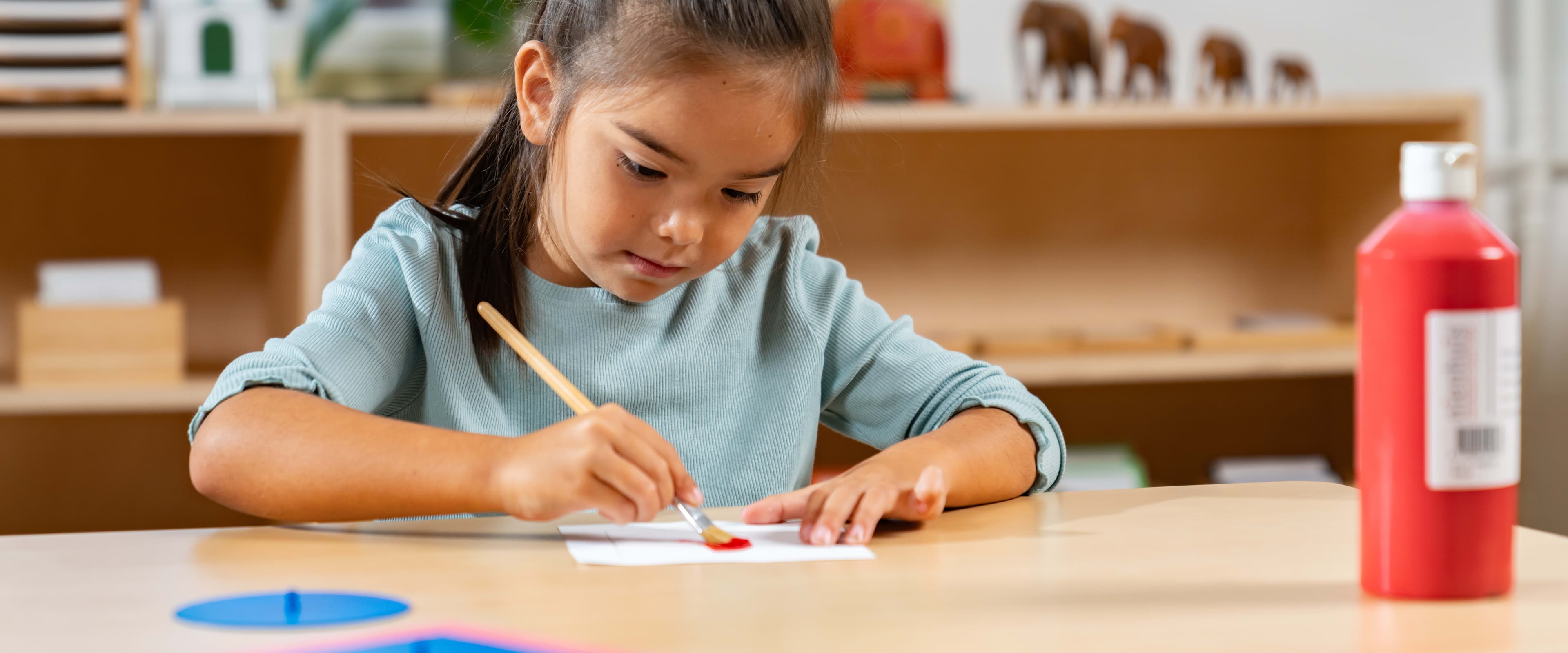Girl painting on a table with red paint