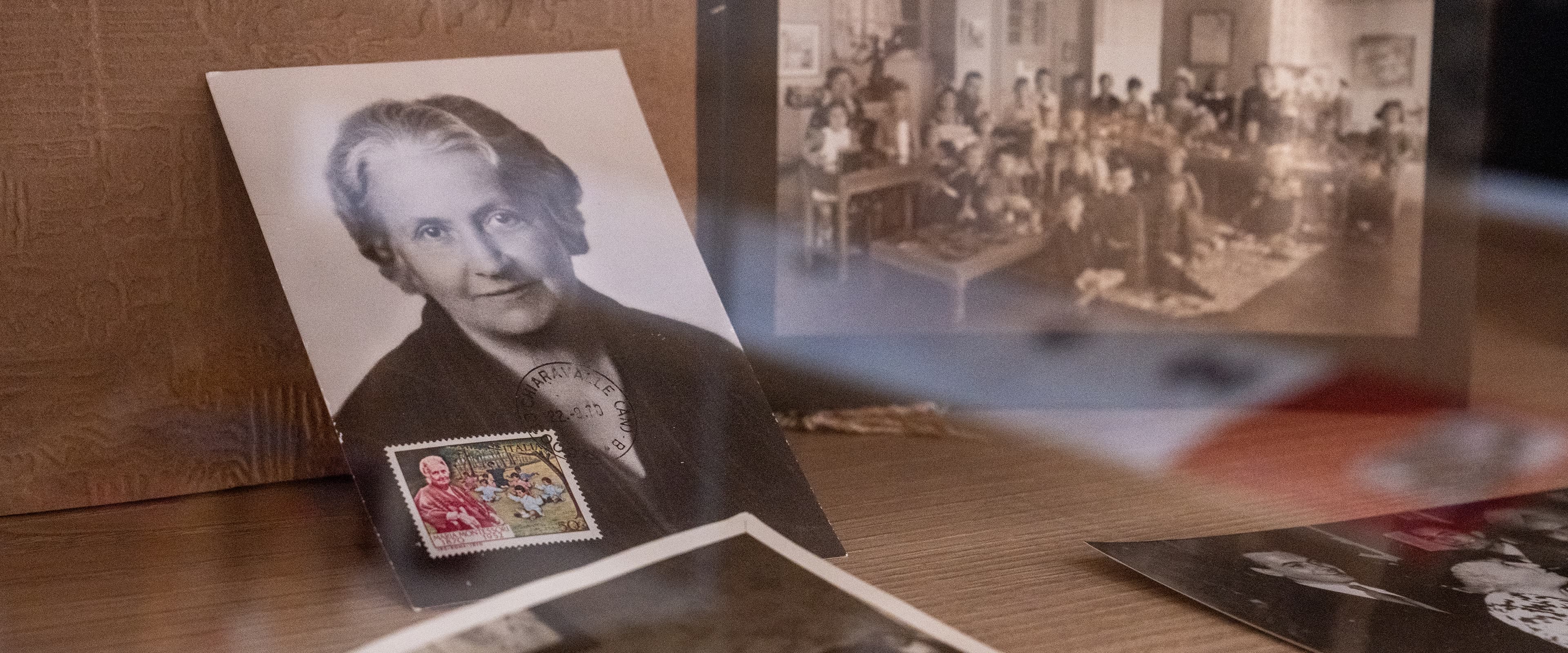 An old photo of Maria Montessori with accompanying stamps and old class photos in the background.